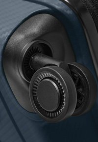Schwarze Kunststoffräder sind an einem blauen, strukturierten Gepäckkörper angebracht. Das Rad hat ein kreisförmiges Design mit spiralförmigen Akzenten für eine sanfte Rotation.