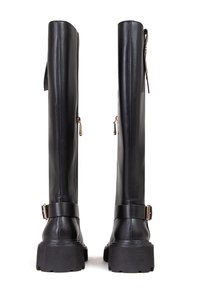 Bottes noires montantes en cuir lisse, avec une semelle épaisse, des zips sur les côtés et une sangle décorative avec une boucle en métal.