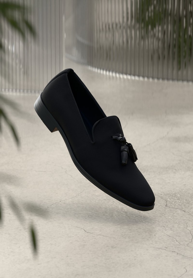 Pantofi loafers negri cu un superior din material neted, vârf ascuțit și ciucuri decorativi. Au un toc mic, rotund și un design minimalistic.