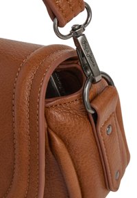 Nahaufnahme einer braunen Leder-Tasche mit genähtem Riemen, einem Metallverschluss mit der Aufschrift "Pepe Jeans" und Nieten an der Leder-Schlaufe.
