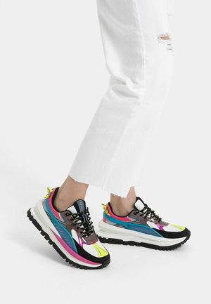 Wielokolorowe sneakersy mają połączenie białego, różowego, niebieskiego i czarnego koloru, z teksturowaną cholewką, czarnymi sznurowadłami oraz grubą białą podeszwą.