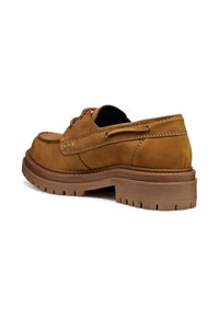 Zapato de ante marrón con punta redondeada, diseño con cordones y suela de goma gruesa con surcos profundos. Costuras visibles a lo largo de los lados.