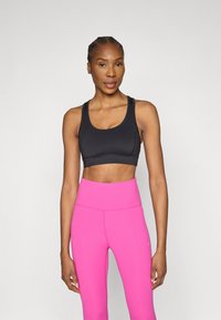 Top sportiv negru, cropped, cu decolteu rotund, asortat cu colanți roz aprins, cu talie înaltă, dintr-un material neted. Design simplu, din țesătură elastică.