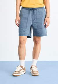 Blå bomullsshorts med elastisk midje og snor, som har to frontlommer og kontrasterende sømdetaljer.