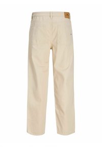 Pantalon décontracté beige avec poches arrière et passants de ceinture, coupe droite, avec un patch de marque marron sur la ceinture.