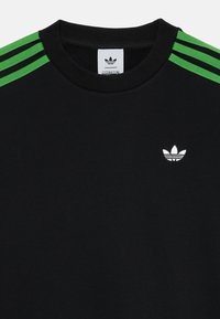Schwarzes Sweatshirt aus Baumwolle mit grünen drei Streifen auf den Schultern und einem kleinen weißen Adidas-Logo auf der Brust.