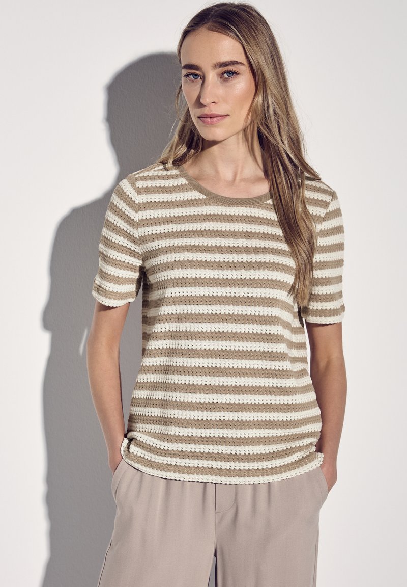 Stricktop mit horizontalen beige- und cremefarbenen Streifen, kurzen Ärmeln und rundem Ausschnitt, kombiniert mit hellen, lässigen Hosen.