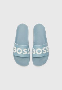 Blå gummisandaler med teksturert fotstøtte og bred stropp som har ordet "BOSS" i store hvite bokstaver.