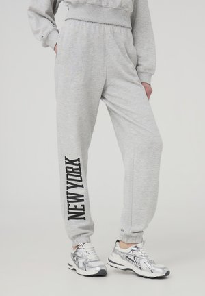 Szare dresy z czarnym nadrukiem "NEW YORK" na lewej nodze, elastycznym pasem i mankietami na kostkach. Miękka tekstura.