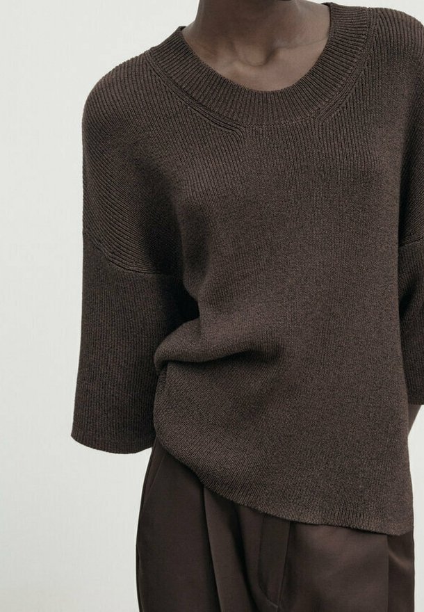 Brun strikket sweater med en bred rund halsudskæring og korte ærmer. Har ribbet tekstur og en afslappet pasform, der er lidt længere bagpå.