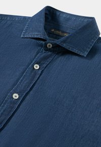 Ciemnoniebieska denimowa koszula zapinana na guziki z ostro zakończonym kołnierzykiem i trzema widocznymi białymi guzikami na przodzie.