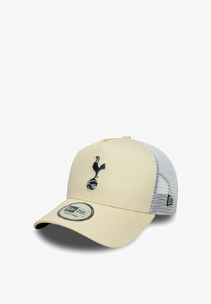 Cremfarbener Baseballschläger mit einem dunkelblauen, gestickten Logo eines Vogels und einem Fußball. Er hat einen weißen Mesh-Rücken und einen gebogenen Schirm.