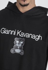 Felpa nera con cappuccio caratterizzata da un grande logo stampato bianco "Gianni Kavanagh" e da una grafica di un orso con occhiali e le braccia incrociate, in grigio.