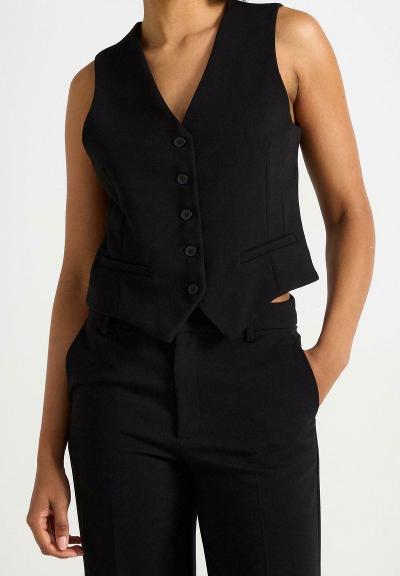Czarna bezrękawnik z dekoltem w kształcie litery V, z przodem zapinanym na sześć guzików, dwiema bocznymi kieszeniami oraz dopasowanym krojem. Gładki materiał z wyraźną strukturą.