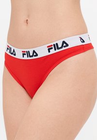 Røde bomullsbikini-briefs med hvit elastisk midjebånd som har "FILA"-logo i marineblått. Har standard snitt med glatt tekstur.