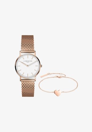 Rosagulds mesh-ur med hvid urskive og minimalistiske timeindikatorer, kombineret med et rosagulds kædearmbånd med en hjerteformet vedhæng.