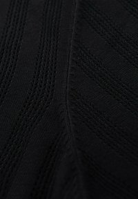 Black knitted fabric with a textured zigzag pattern, featuring vertical and diagonal lines, smooth surface, and slight sheen.
