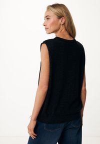 Suéter negro sin mangas con cuello redondo, hecho de una tela suave. La parte posterior presenta un ajuste relajado y detalles de diseño minimalistas.