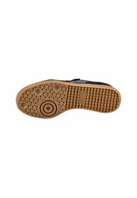 Suola nera di sneakers con un fondo di gomma testurizzata, caratterizzata da motivi circolari e esagonali, e accenti di gomma naturale.