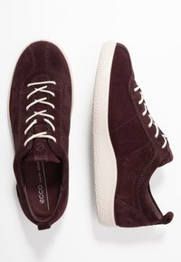 Bordové semišové tenisky s bílými tkaničkami a gumovou podrážkou; zaoblená špička a polstrovaný límec; logo na patě a bočních panelech.