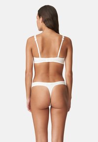 Wit kanten bh en slipset met bloemaccenten, verstelbare banden en een geruite textuur. Beide kledingstukken hebben een delicate afwerking.