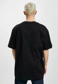 Sort oversized t-shirt med korte ærmer, rund halsudskæring og lige kant, lavet af bomuldsstof. Ingen synlige logoer eller mønstre.