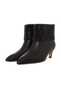 Botines de cuero negro con un puño texturizado negro con tachuelas, punta afilada y tacón bajo. Acabado liso con detalles pulidos.