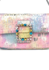 Bolso rectangular en colores pastel con una textura estampada. Cuenta con una hebilla plateada brillante adornada con coloridos rhinestones.