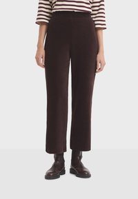 Woman wearing dark brown ribbed wide-leg pants, brown leather ankle boots, and a white and burgundy striped shirt with three-quarter sleeves.