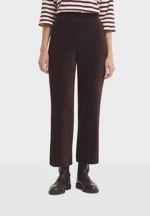 Woman wearing dark brown ribbed wide-leg pants, brown leather ankle boots, and a white and burgundy striped shirt with three-quarter sleeves.