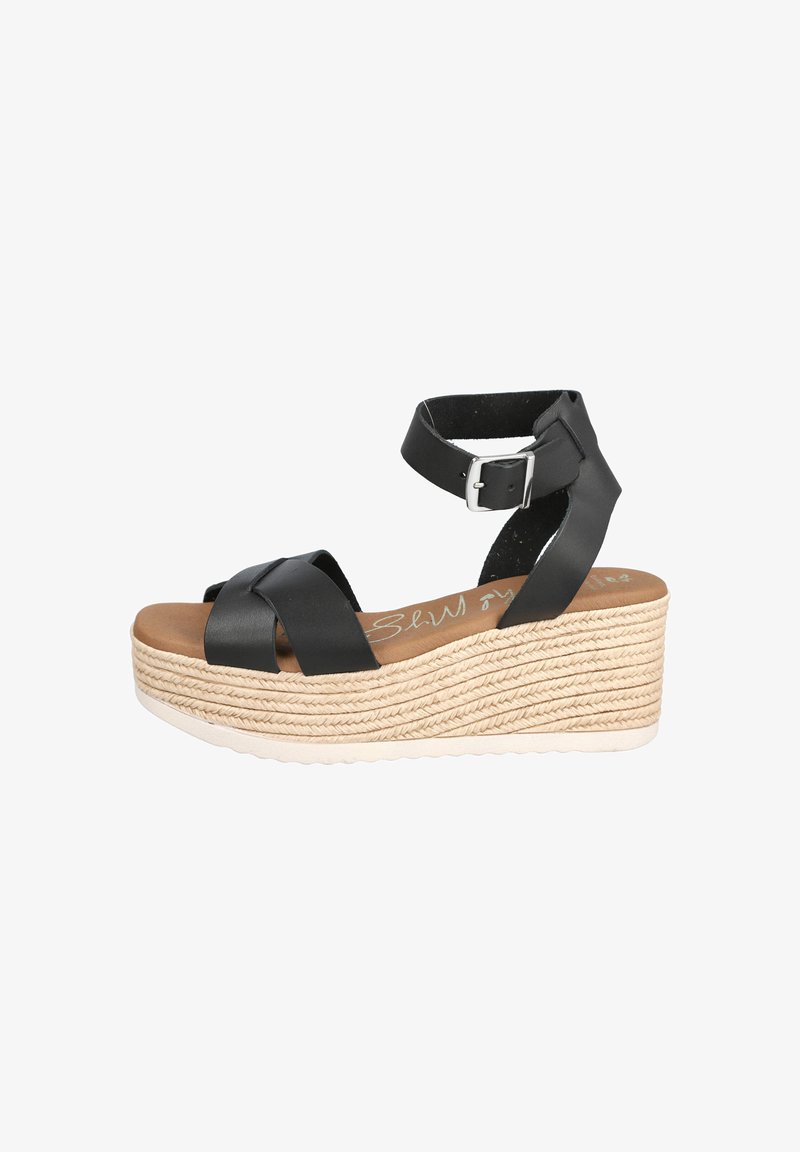 Sandalias de cuña de cuero negro con tiras cruzadas, correa ajustable en el tobillo y suela envuelta en yute texturizado. Plantilla acolchada de color marrón claro.