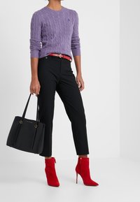 Lila kabelstickad tröja, svarta skräddarsydda byxor, röd läderbälte, röda mocka ankelförankrade stövlar med stilettklackar och en svart tote-väska.