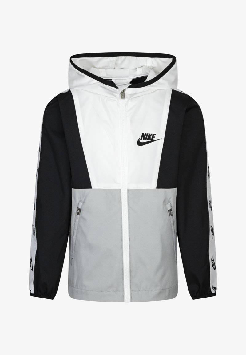 Nike vėjaraštis su spalvų blokavimo dizainu baltos, juodos ir pilkos spalvų. Jis turi gobtuvą, užtrauktuko uždarymą ir logotipo akcentus ant rankovių.