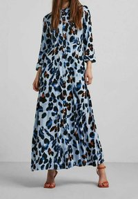 Abito camicia leggero di colore azzurro con motivo leopardato in nero, blu e marrone. Maniche lunghe e design fluido che arriva alle caviglie.