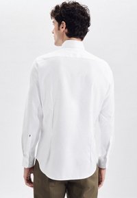 Witte lange mouwen shirt met een subtiele glans, met knoopmanchetten, een puntige kraag en een afgeronde zoom. De achterkant toont schone, op maat gemaakte lijnen.