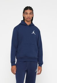 Hanorac bleu marin cu buzunar tip kangaroo, manșete ribbate și logo alb Jordan pe piept. Material moale cu o potrivire relaxată.