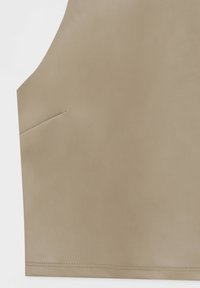 Haut en cuir beige avec une texture lisse, présentant une encolure arrondie et une poche latérale. Des coutures décoratives courant le long du bord.