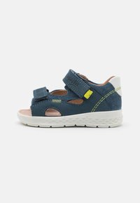 Blue suede sandal with open design, adjustable strap, white accents, and a textured white sole for grip; features a small logo on the strap.