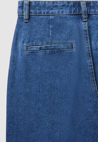 Jeans in denim blu con una texture liscia, dotati di una singola tasca posteriore con patta e cuciture visibili.