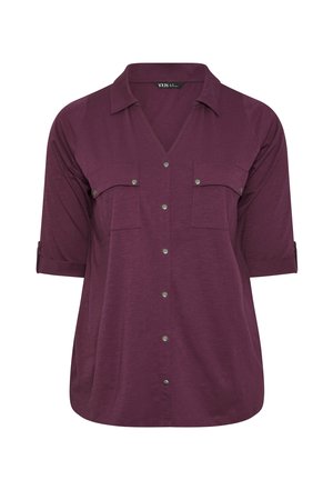 Camicia bordeaux con colletto a V, due taschini sul petto e maniche arrotolate. Realizzata in un tessuto morbido e texturizzato. Bottoni a pressione in metallo argento.