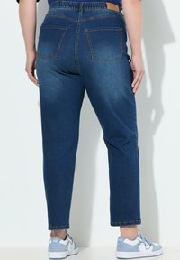 Pantalones de mezclilla azul oscuro con cintura elástica, que cuentan con dos bolsillos traseros. La tela tiene una textura suave con un ligero efecto de decoloración.