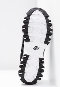 Black and white athletic shoe outsole featuring textured rubber with a patterned grip, midsole cushioning, and a prominent "S" logo.