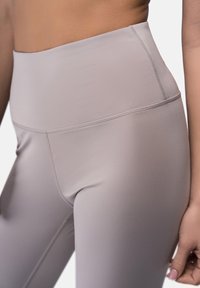 Leggings de tiro alto en gris claro, hechos de una tela suave y elástica con costuras planas. Presentan un diseño sin costuras y un ajuste que se adapta al cuerpo.