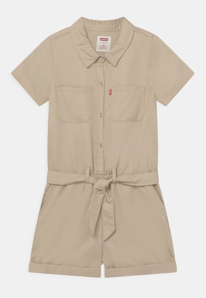 Beżowy kombinezon z krótkim rękawem, kołnierzykiem, dwiema kieszeniami na piersi, paskiem w talii oraz podwiniętymi mankietami. Wykonany z gładkiego materiału.