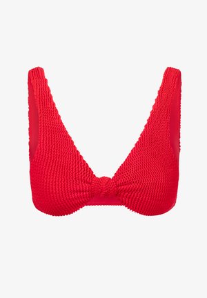 Haut de bikini rouge texturé avec de larges bretelles, décolleté en V plongeant et un détail noué au centre. Le matériau semble extensible et ajusté.