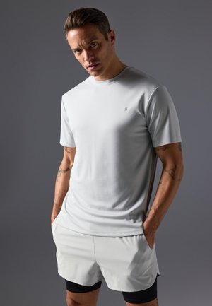 Light grey athletic t-shirt with a crew neck and short sleeves, paired with light grey shorts. Features subtle branding and a smooth texture.