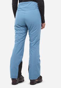 Pantalons de ski isolés bleus avec une taille haute, accents noirs aux poignets, et une texture lisse et légèrement brillante. Équipés de coutures renforcées.