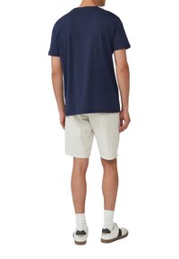 Navy Baumwoll-T-Shirt mit klassischer Passform, kurzen Ärmeln und rundem Ausschnitt, kombiniert mit weißen Shorts und Sneakers mit schwarzen Akzenten.