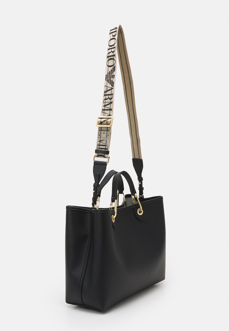 Borsa tote in pelle nera con hardware dorato, doppi manici superiori e una tracolla rimovibile con stampa del logo e design a strisce.