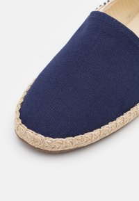 Marineblaues Canvas-Espadrille mit einer strukturierten Oberseite und einer natürlichen Jutekordelsohle, mit einer abgerundeten Zehenpartie und genähten Details am Rand.